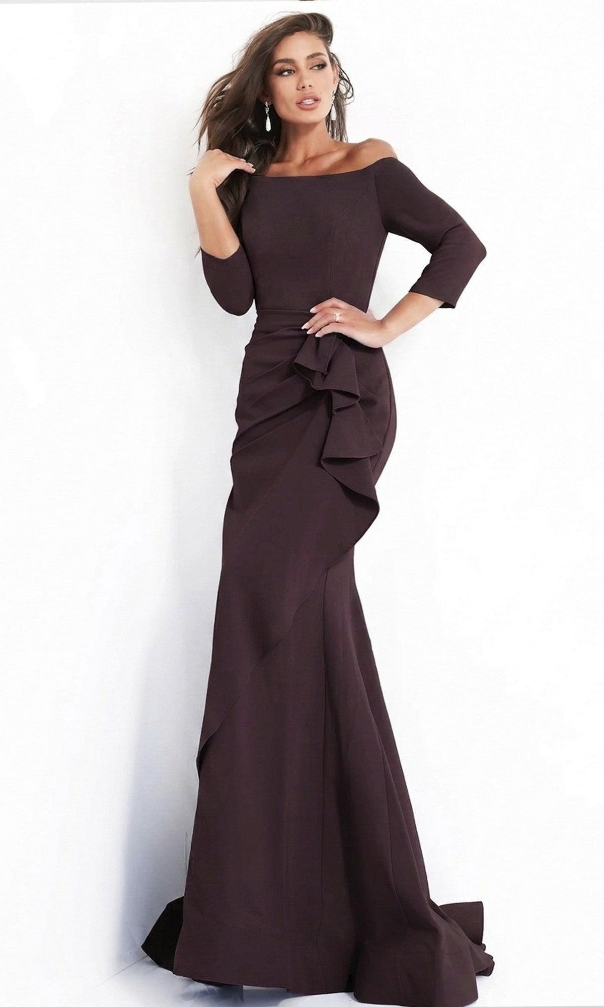 A woman wearing the Jovani Mother-of-the-Bride Long Formal Dress 00446 in plum—an off-the-shoulder, floor-length evening gown featuring three-quarter sleeves and ruffle detail—stands against a white background.